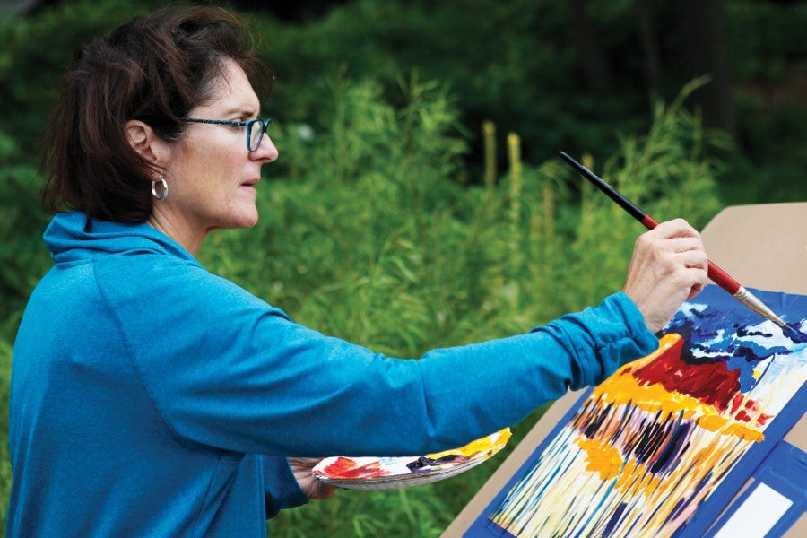 woman painting canvas with acrylics during class at college of creative arts