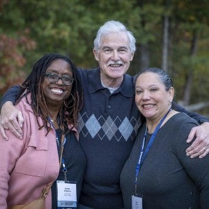 Three alumni stand outdoors.