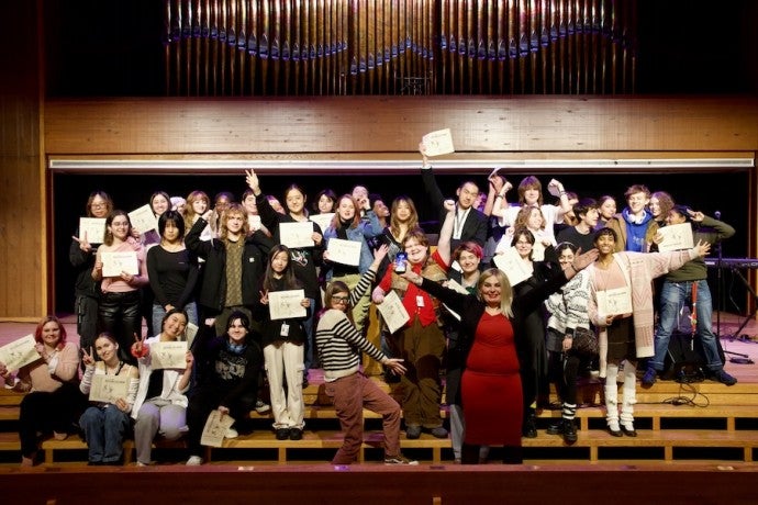 A large group of students and instructors poses expressively for the camera.