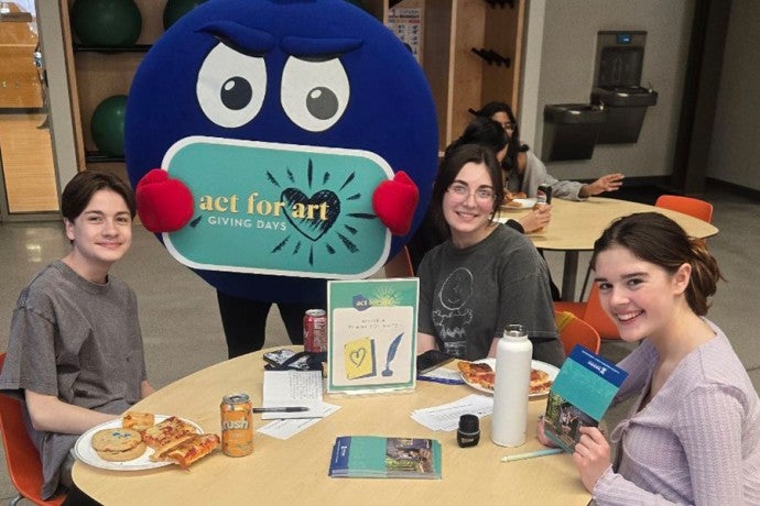Students at a volunteer station during the Act for Art kickoff party, writing thank you notes and hanging out with Denny the Blueberry