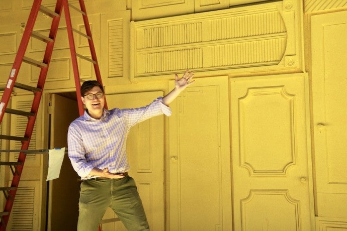 Set designer Edward T. Morris gestures toward the vivid yellow set of The Comedy of Errors.