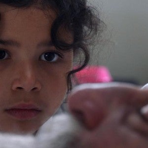 A young girl looks intently at a man's face