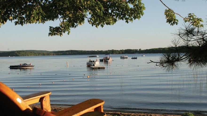 Several boats float on a gently rippling lake