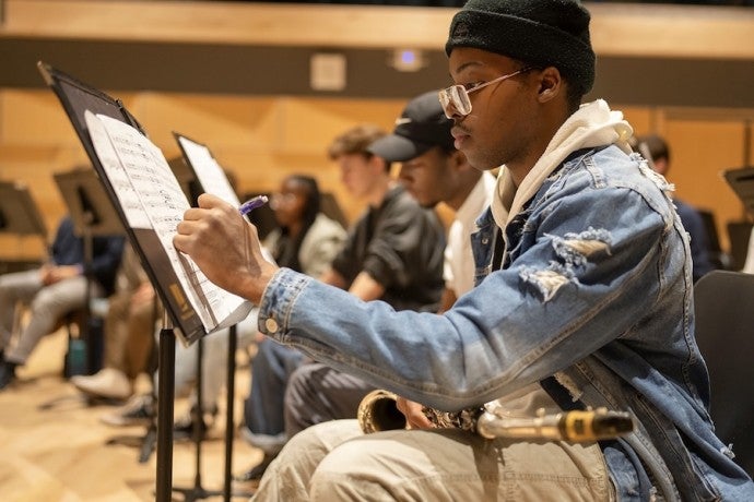 A saxophone student makes notes on sheet music.