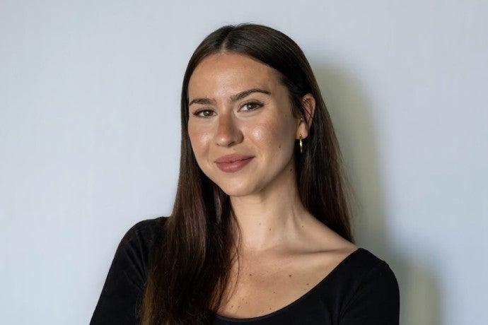 A dark-haired young woman smiles into the camera.