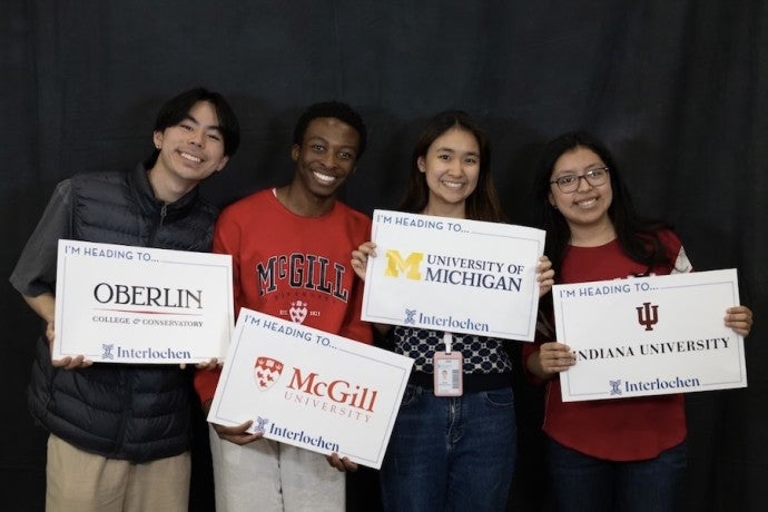 Students show off signs from the colleges to which they have been admitted.