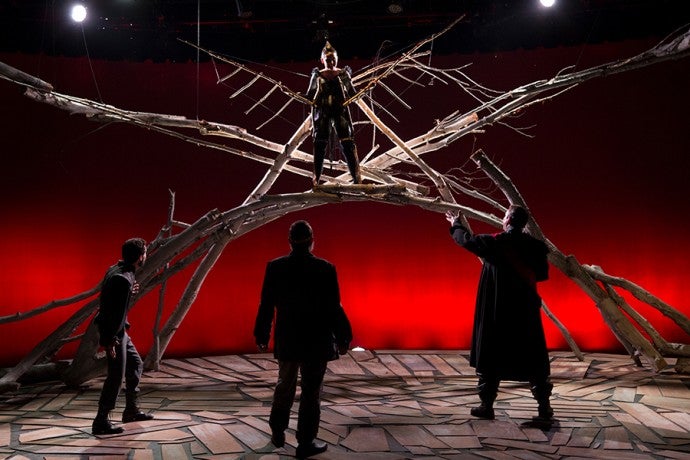 three men stand before a figure in the trees